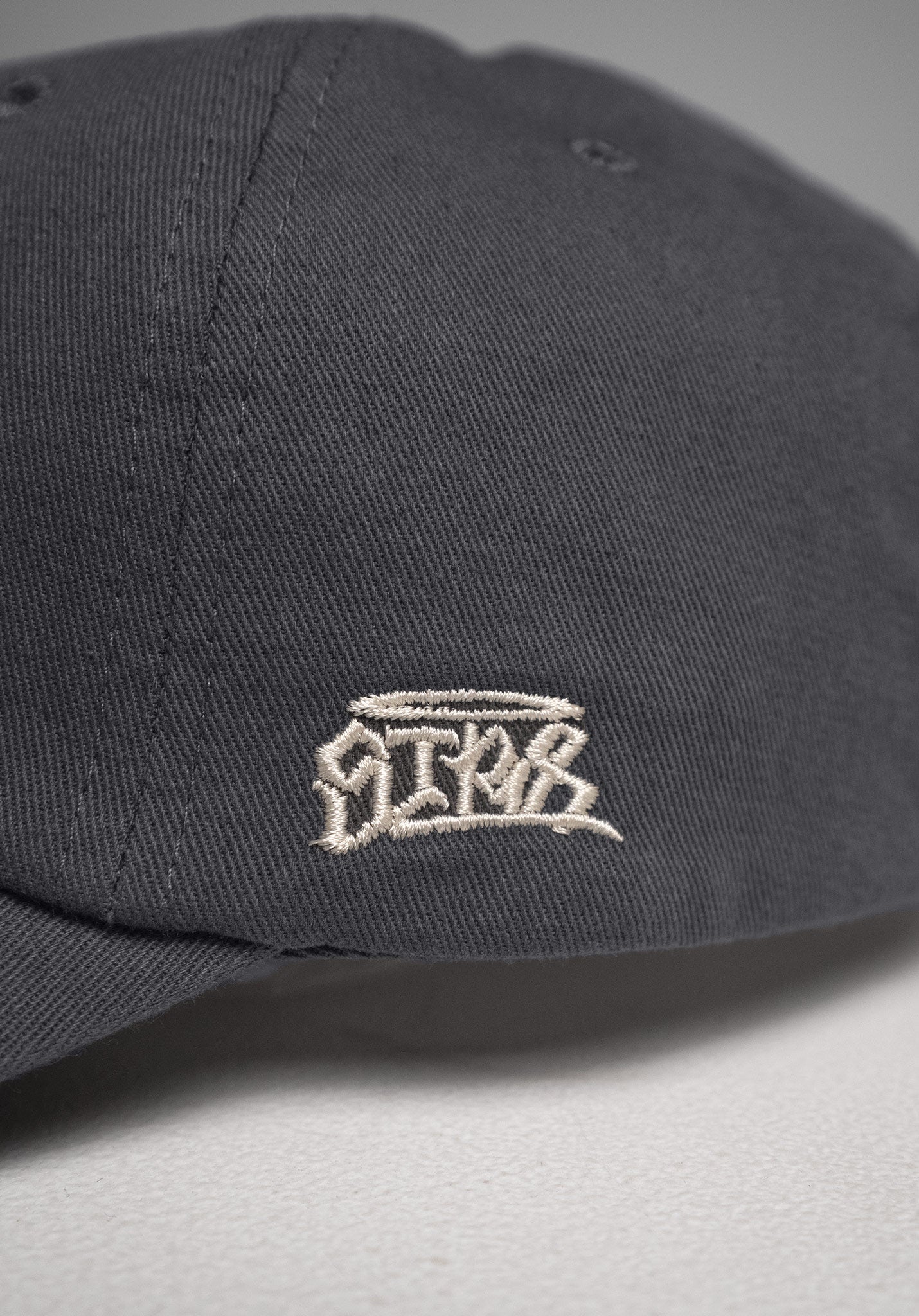 6 Panel Cap „Str8" in Cool Grey – Detailansicht der seitlichen Stickerei „Straight – Str8"